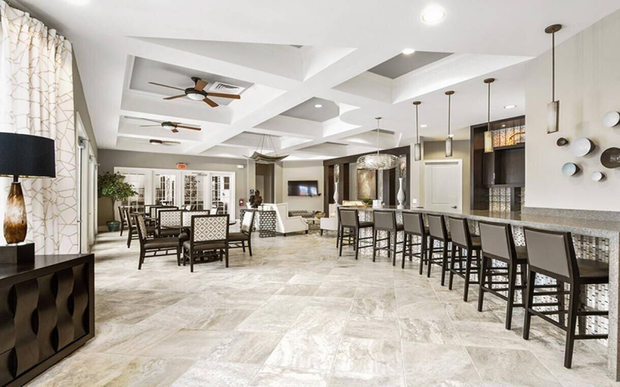 A spacious kitchen with a long bar, modern ceiling design, and a dining area with a large table and chairs.