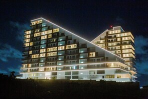 Een modern hotel met meerdere verdiepingen, verlichte balkons en een opvallend geometrisch ontwerp.