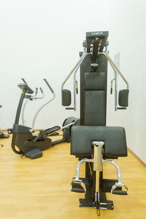 Academia com equipamentos de exercícios, incluindo bicicleta ergométrica, elíptico e máquina de musculação.