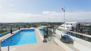 Ein Dachpool mit Glasgeländern, ein überdachtes Auto und Blick auf die Stadtlandschaft.