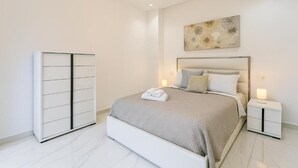 Een moderne slaapkamer met een groot bed, nachtkastjes, een garderobe en een plafondlamp.