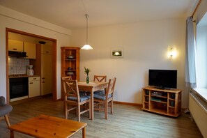 A compact living space with a dining area, kitchen, and a television.