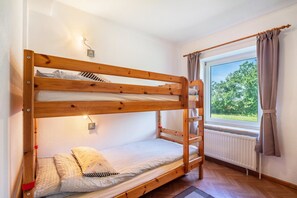 Ein Etagenbett mit einer Leiter, einem Fenster mit Vorhängen und einer Heizung.