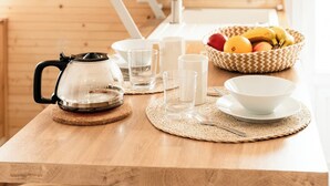 Ett kök med träinredning, en kaffebryggare, en skål med frukt och ett handfat.