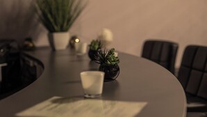 Une table de conférence avec un document, un verre d’eau et deux petites plantes en pot.
