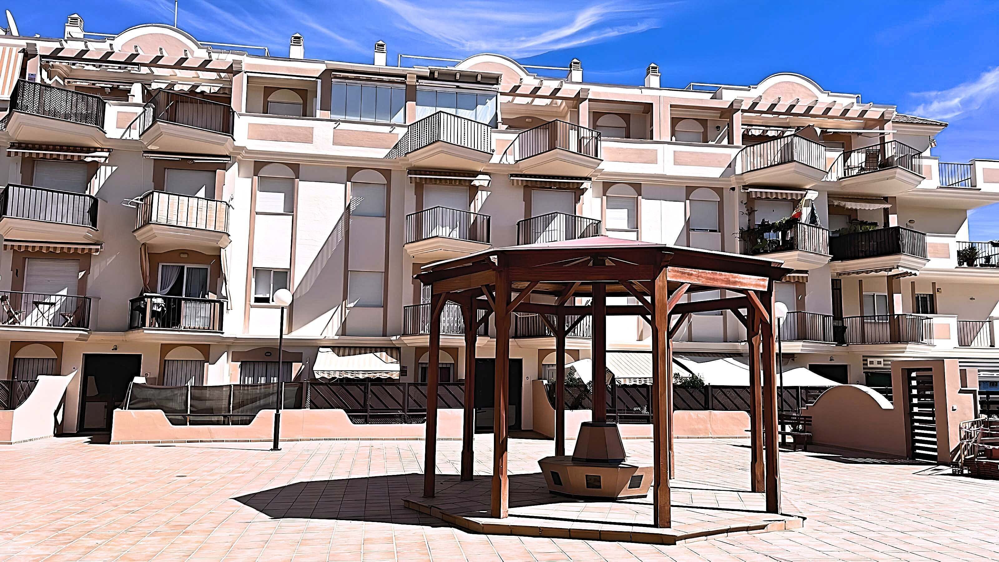 Un edificio residenziale a più piani con balconi, una zona relax all'aperto coperta e un patio piastrellato.