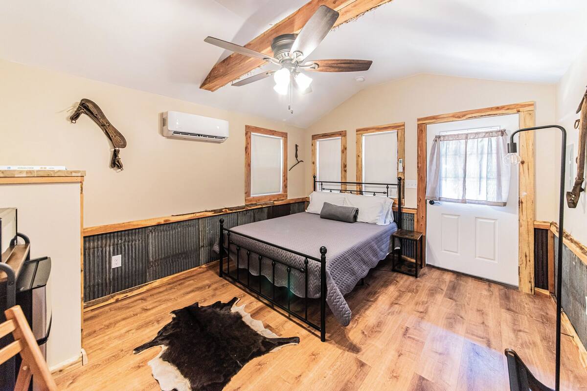 A bedroom with a bed, a ceiling fan, a window, and a door.