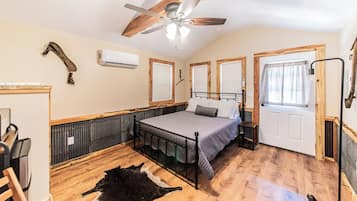 A bedroom with a bed, a ceiling fan, a window, and a door.