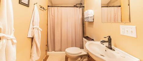 A bathroom with a toilet, sink, and shower curtain.