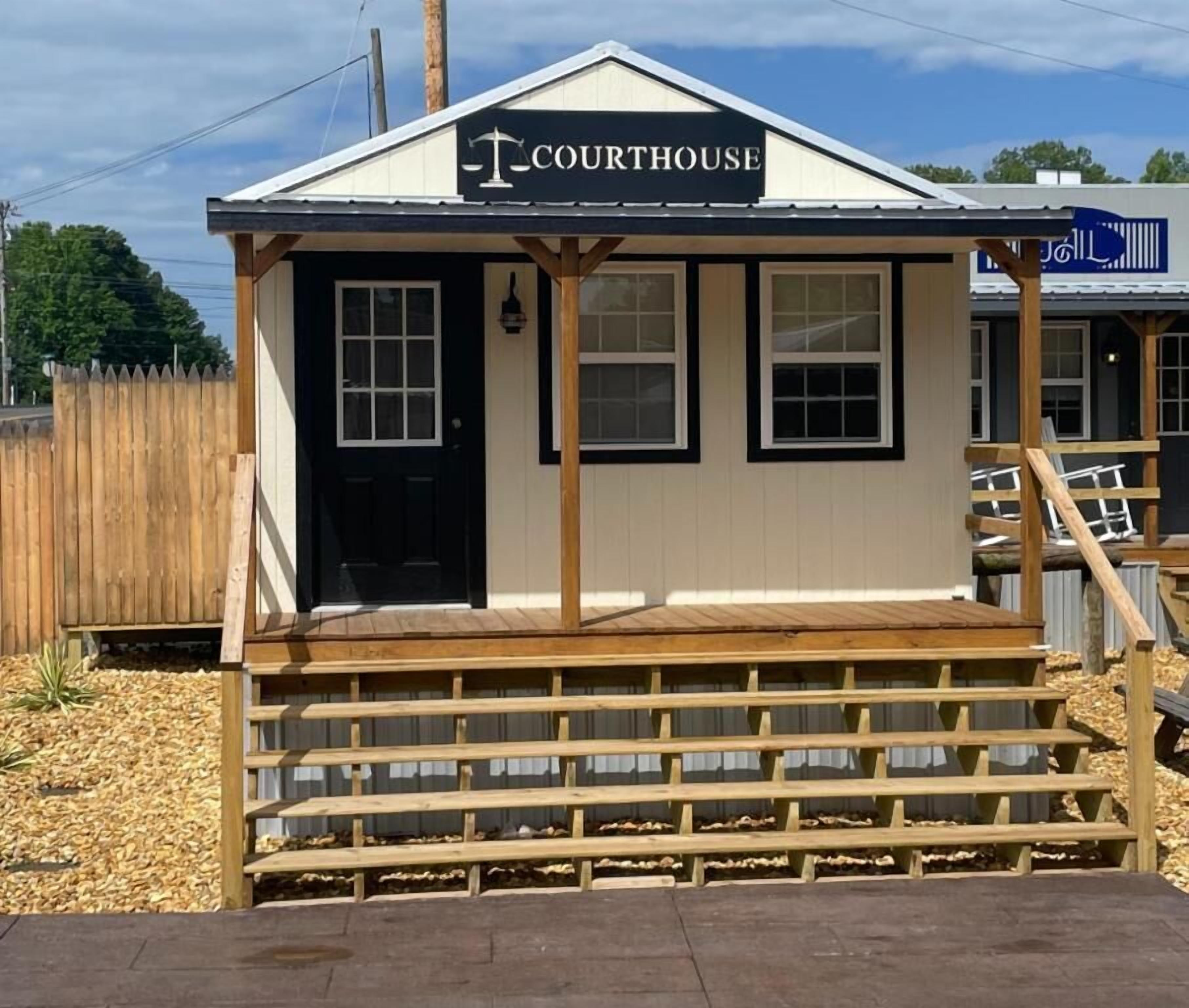 A small, single-story building labeled "COURTHOUSE" with a wooden porch and a black door.