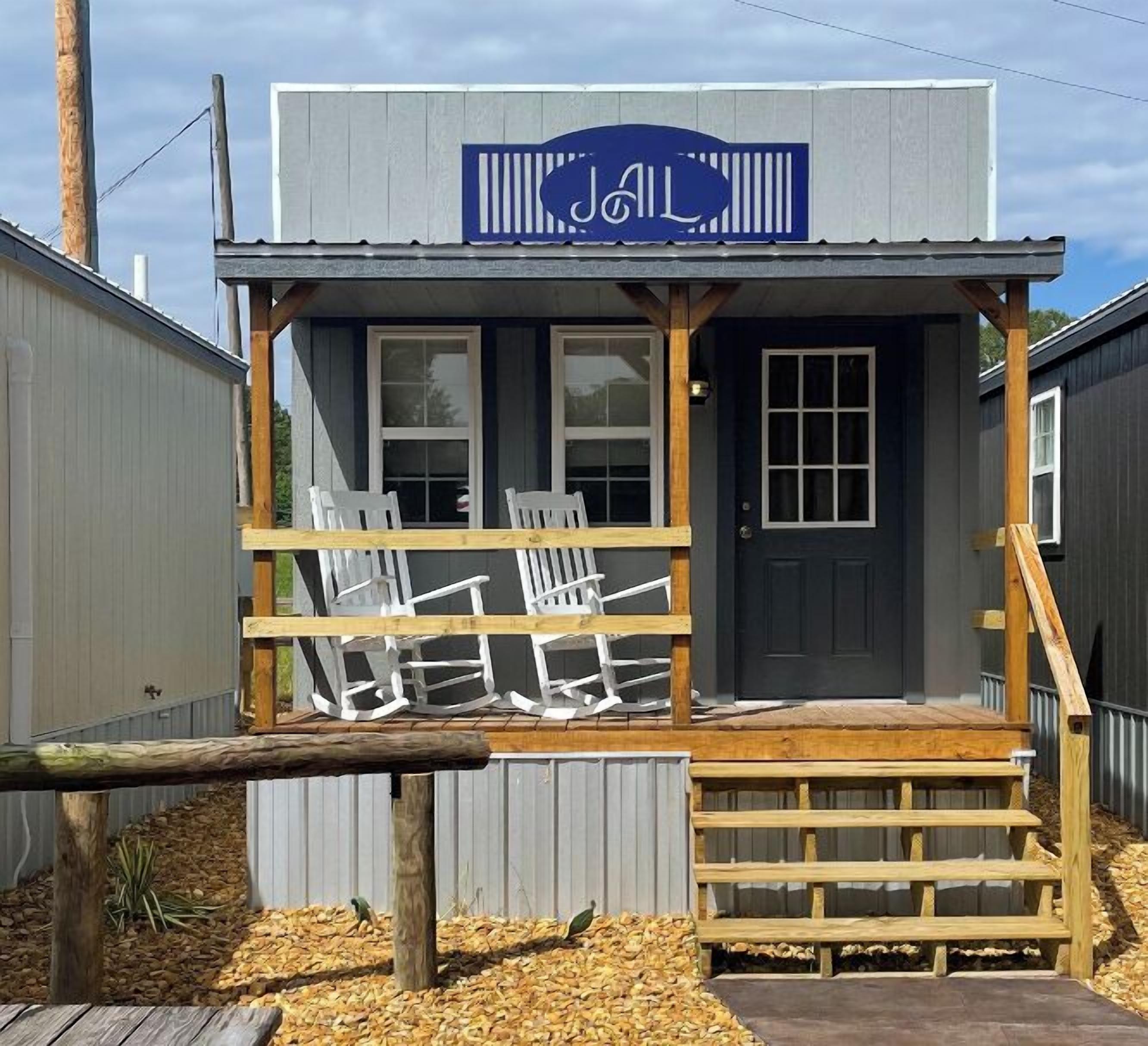 A small building with a porch, a sign above the entrance, and a wooden bench in front.