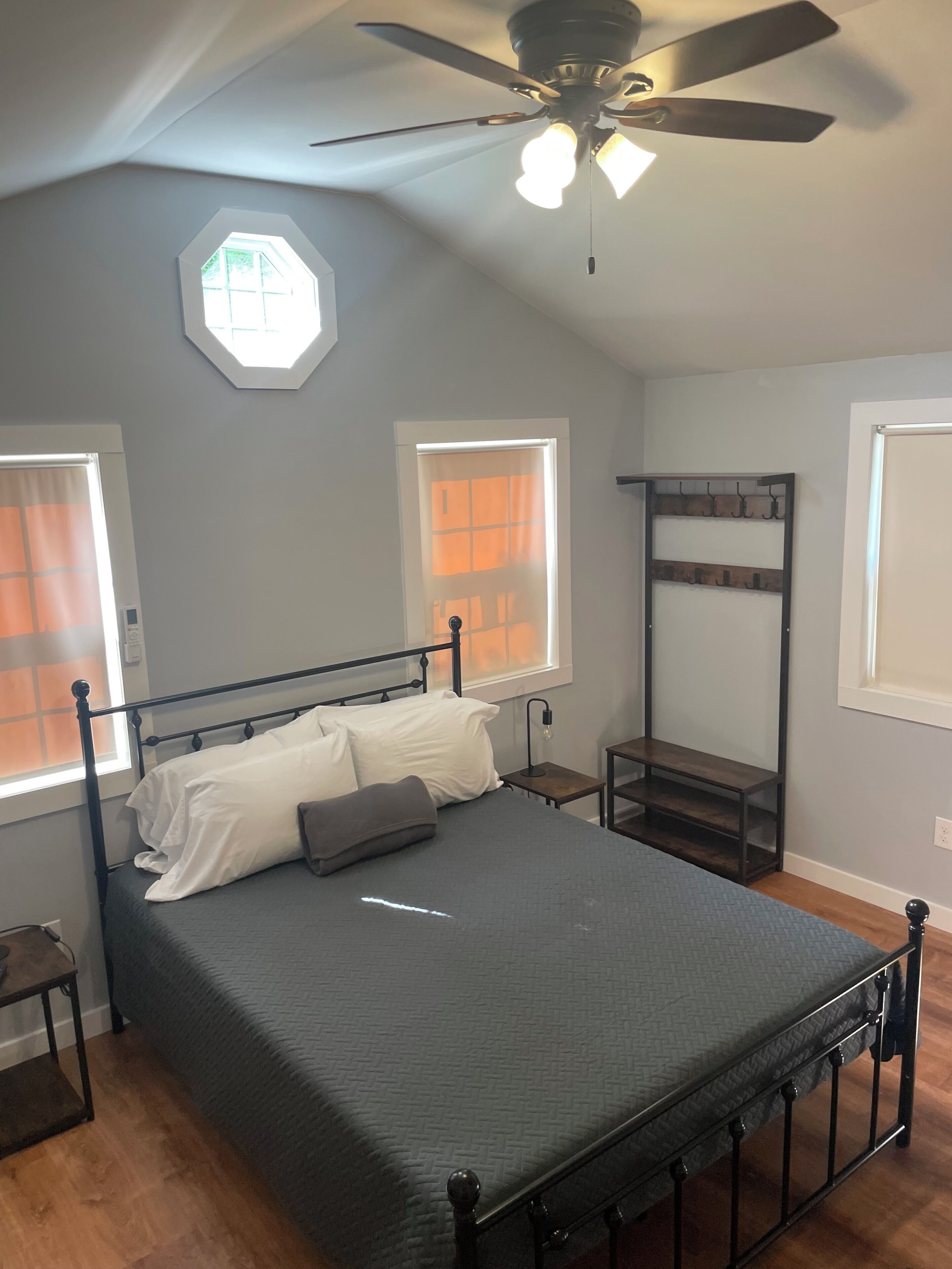 A bedroom with a bed, a ceiling fan, and a window with curtains.