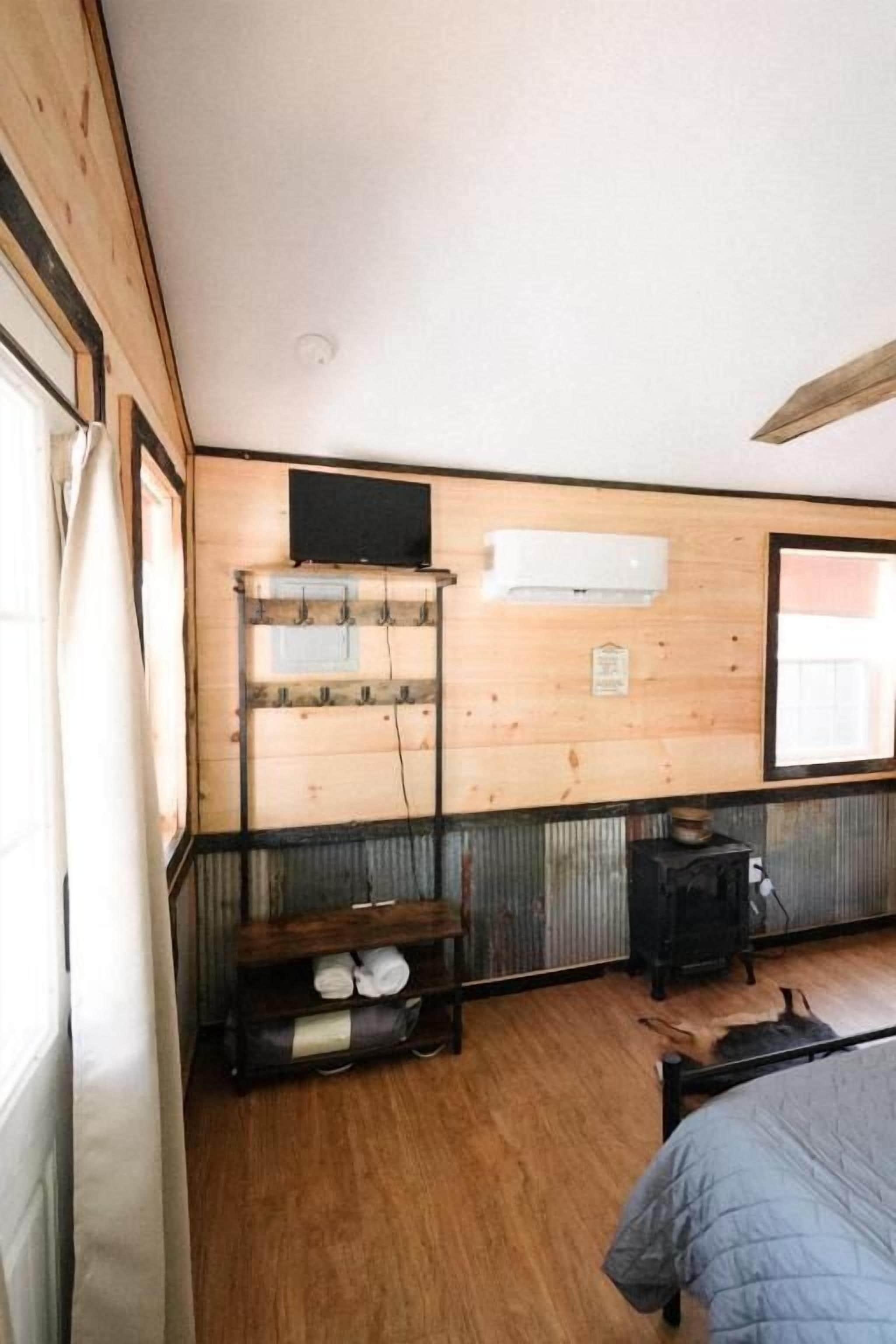 A room with a bed, a wooden shelf with hooks, a radiator, and a window.