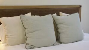 Un llit amb roba de llit blanca i un capçal de fusta.