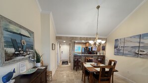 Ein geräumiger Essbereich mit hoher Decke und einer Chandelier-Leuchtreiter, der zu einer Küche mit Kochinsel und Blick auf den angrenzenden Wohnbereich führt.