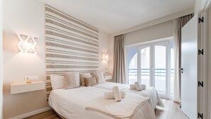 A modern bedroom with a large bed, a striped wall, and a view of the outdoors. - MalagaSuite Duplex Marbella with Parking (Marbella)