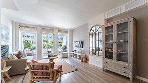A spacious living room with a wooden floor, a large cabinet with glass doors, and a sofa. - MalagaSuite Duplex Marbella with Parking (Marbella)