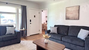 Ein modernes Wohnzimmer mit zwei Sofas, einem Couchtisch und einem Essbereich im Hintergrund.