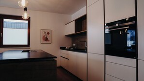 A modern kitchen with a black countertop, white cabinets, and a built-in oven. - Apart Veronika - Exclusive living in Imst (Gemeinde Imst)