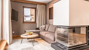 Una sala de estar moderna con un sofá seccional, una chimenea de vidrio y vistas al exterior.