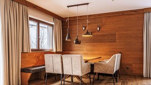 Un área de comedor moderna con un banco de madera, una mesa y cuatro sillas.