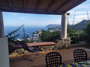 A covered outdoor seating area with a view of the sea and a mountain. - Apartment in Villa "Panarea" with Sea View, Wi-Fi and Air Conditioning (Lipari)