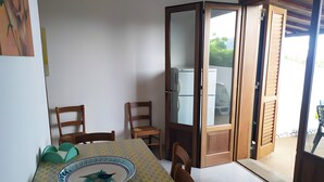 Un coin repas comprenant une table, des chaises, un meuble avec des portes en verre et une vue à travers la vitre.