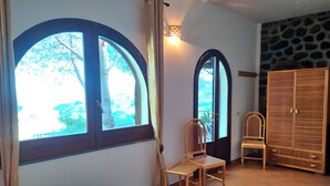 A room with two large arched windows, a bed, a wardrobe, and a small table. - Apartment in Villa "Stromboli" with Sea View, Wi-Fi and Air Conditioning (Lipari)