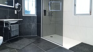 A modern bathroom with a glass-enclosed shower, a vanity with a mirror, and a window providing natural light. - Terra Nova Casa - Free parking 24/24 (Pau)