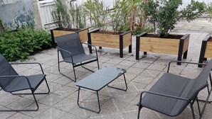 Outdoor seating with metal chairs and a table, surrounded by planters with various plants. - Terra Nova Casa - Free parking 24/24 (Pau)