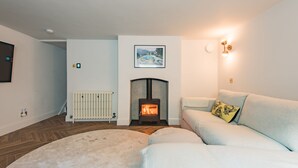 A living room with a fireplace, a sofa, a rug, and a picture on the wall. - Penshurst House Deal, Kent (Deal)