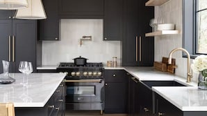 A modern kitchen with dark cabinetry, a central island, and a built-in oven. - Lux 5BR South Peak Loon - riverfront w swimming and beach - hot tub - pets ok (Lincoln)