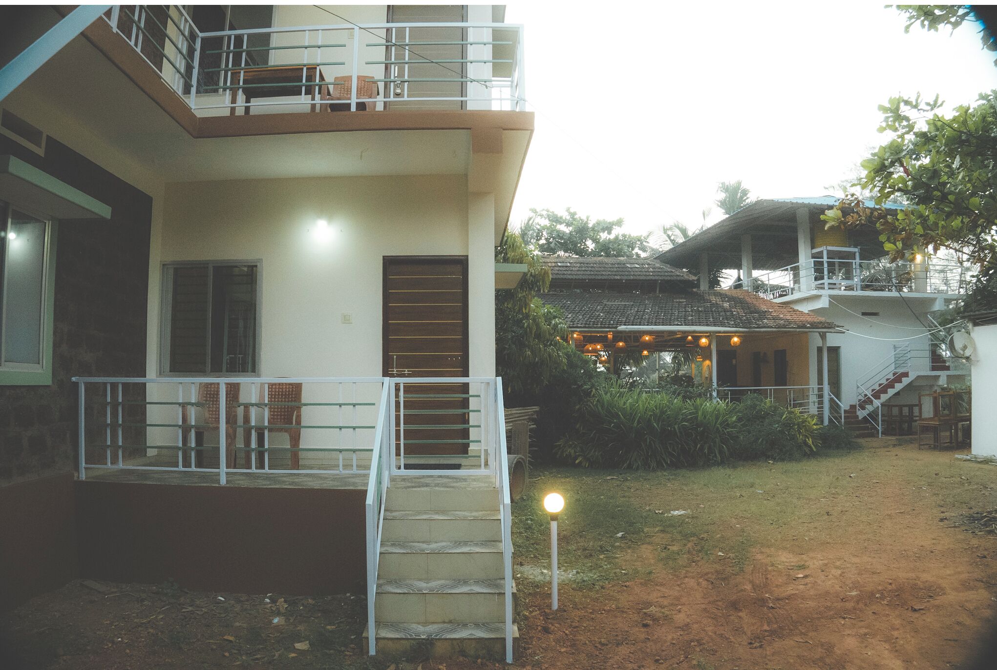 A two-story building with a balcony, a staircase, and a covered outdoor seating area.