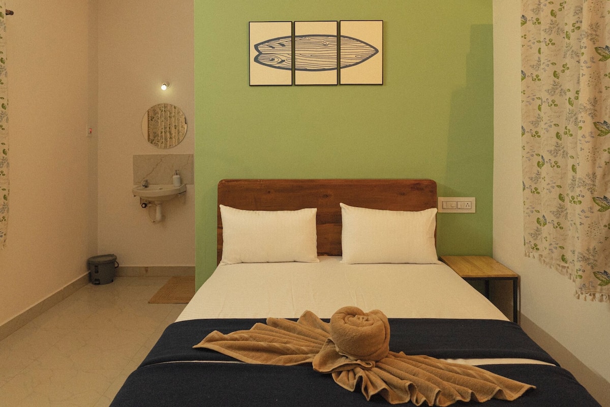 A hotel room with a bed, a nightstand, a sink, and a mirror.