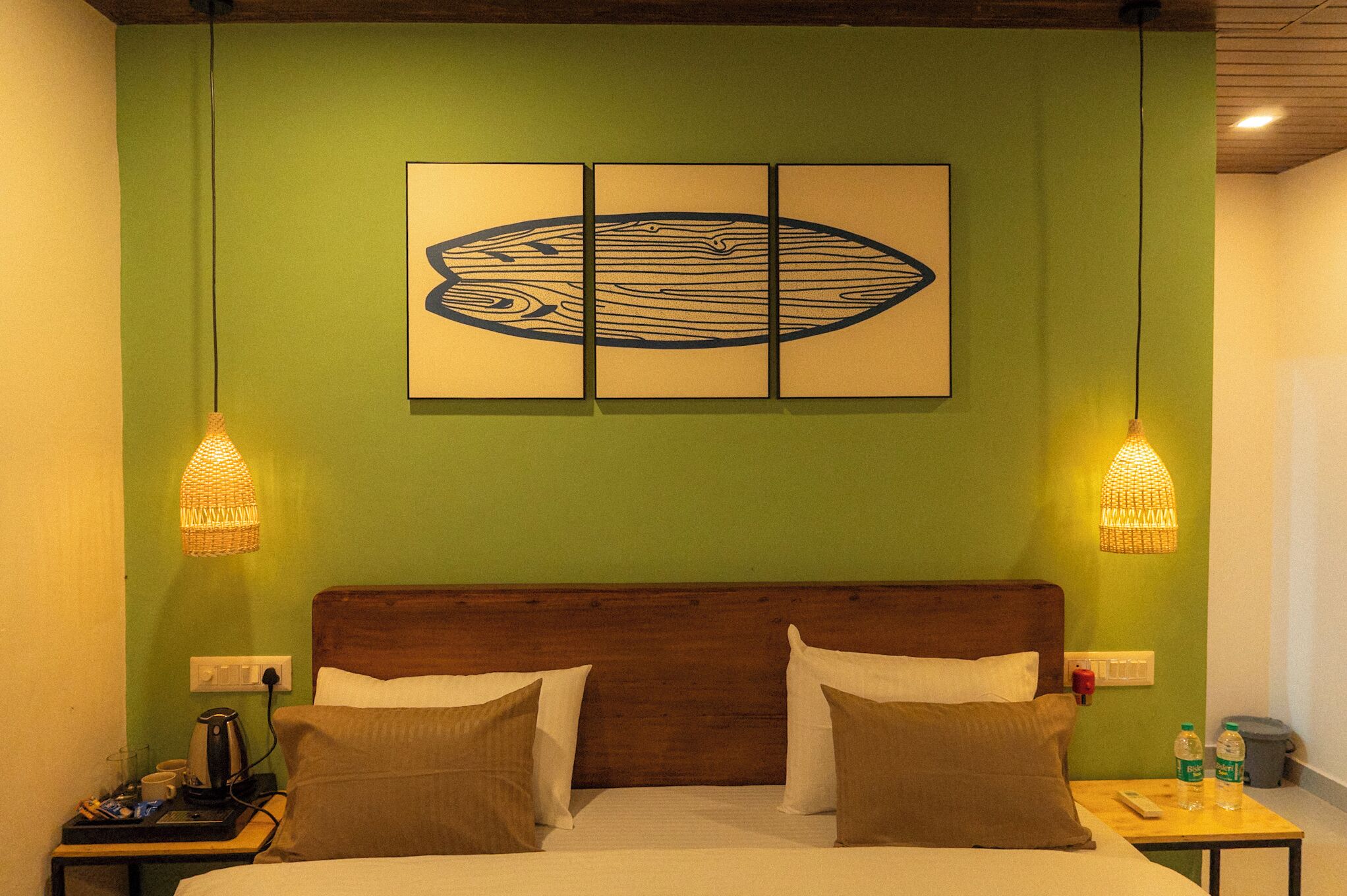 Une chambre d’hôtel comprenant un lit, deux lampes de chevet, une table de chevet avec une machine à café et une œuvre d’art décorative accrochée au mur au-dessus du lit.