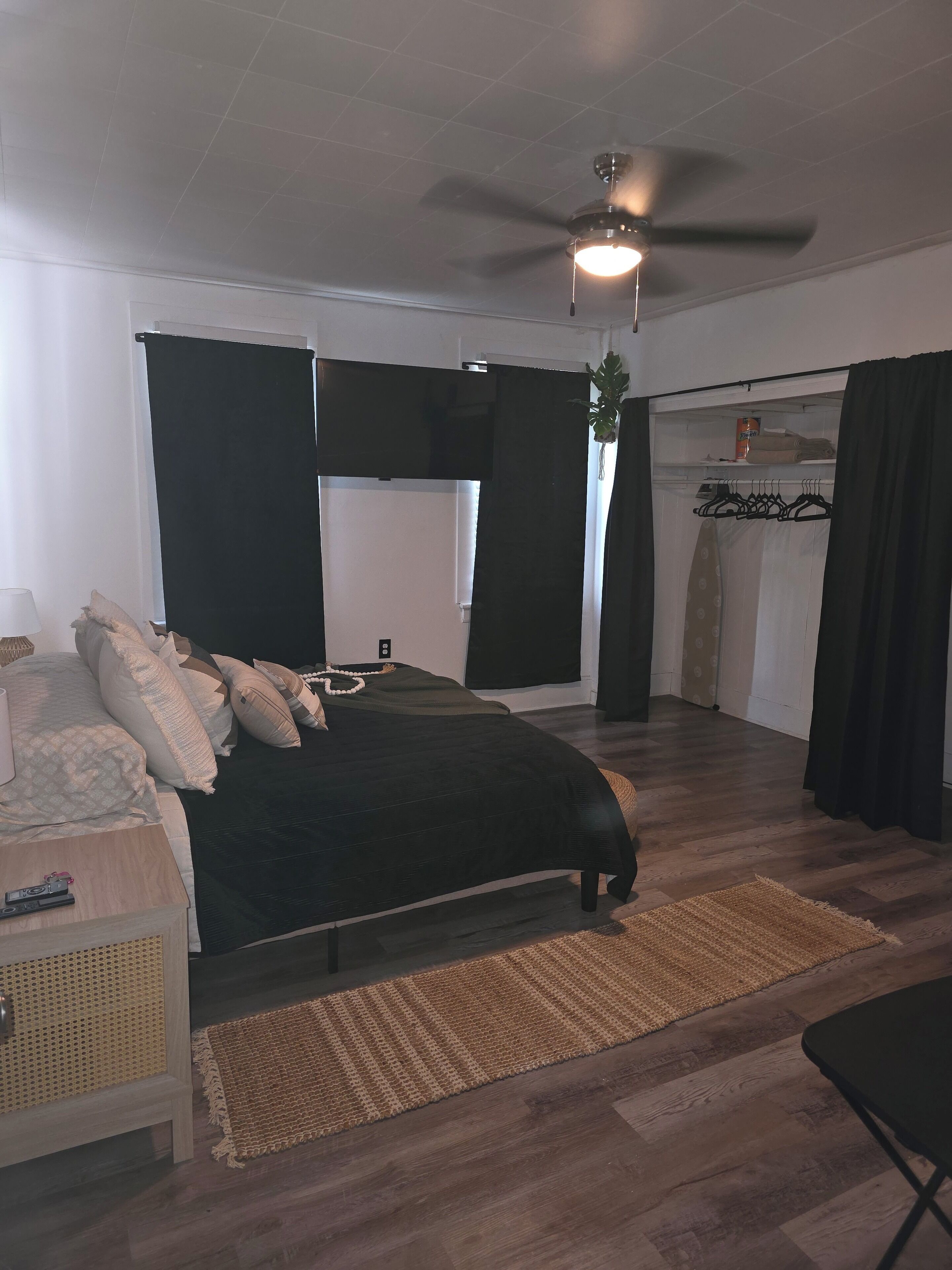 A bedroom with a bed, a bedside table, a ceiling fan, and a wardrobe.