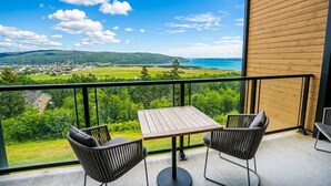 Ein Balkon mit Tisch und Stühlen, der Blick auf eine Küstenlandschaft bietet.