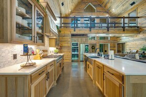 A spacious kitchen with wooden cabinetry, a central island, and a mezzanine level with a balcony. - ATP~4Kings+bunkroom~Sleeps16~Pickleball~Hottub (Broken Bow)