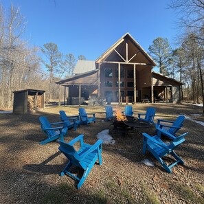 Uma cabana com lareira e cadeiras Adirondack azuis na frente.