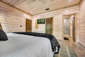 Quarto de cabana de madeira com cama, porta e janela.