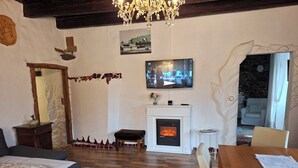 Una sala de estar acogedora con chimenea, un televisor montado encima y un comedor con mesa y sillas de madera.