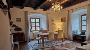 Una habitación acogedora con una mesa de comedor de madera, sillas, una araña y un sofá.