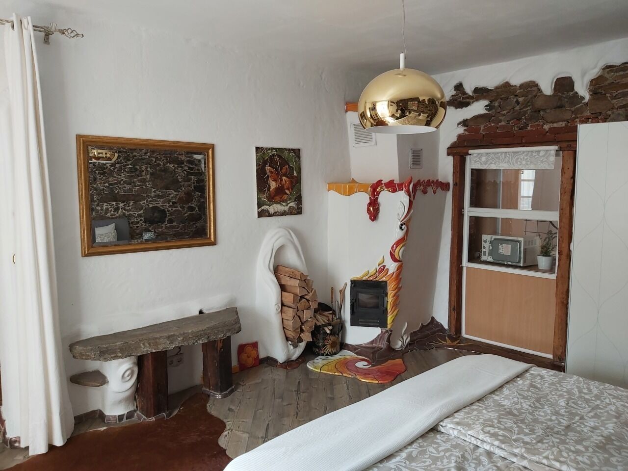 Une chambre à coucher comprenant un lit, un banc, une cheminée, un miroir et une étagère avec divers objets.
