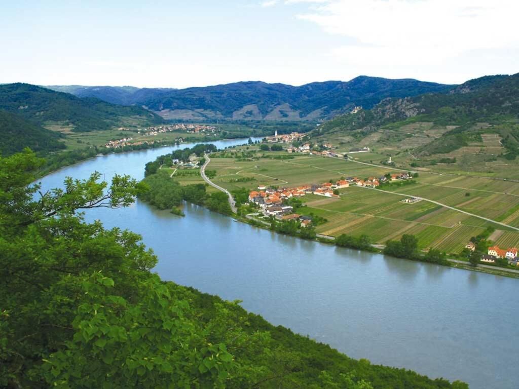 Een rivier slingert door een vallei met een klein stadje en velden.