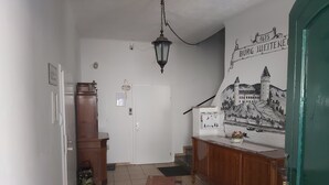 Un pasillo con un armario de madera, una puerta blanca y un mural en la pared que representa una escena histórica.