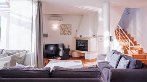 Uma sala de estar moderna com sofá, televisão, lareira e escada.