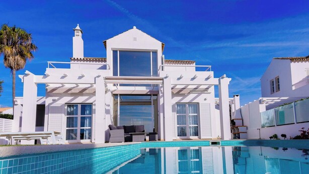 Um edifício branco moderno com piscina em frente.