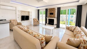 Ein geräumiges Wohnzimmer mit Kamin, Flachbildfernseher und Essbereich.