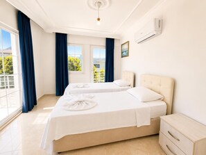 Habitación de hotel con dos camas, una mesita de noche, un aparador, un ventilador de techo y vistas a zonas verdes.