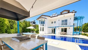 Ein Poolbereich mit Tisch und Stühlen, einem Pool und einem zweistöckigen Gebäude mit Balkonen.